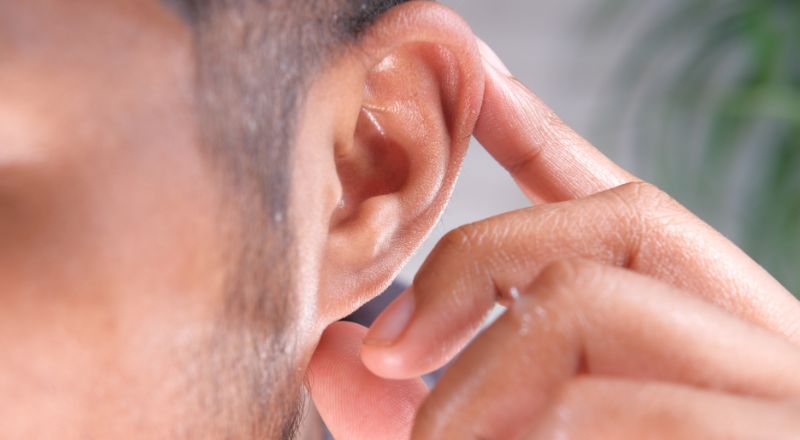 A person holding their ear, trying to capture a distant sound